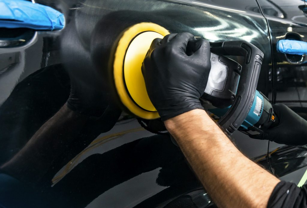 Buffing and polishing car. Car detailing. Man holds a polisher in the hand and polishes the car