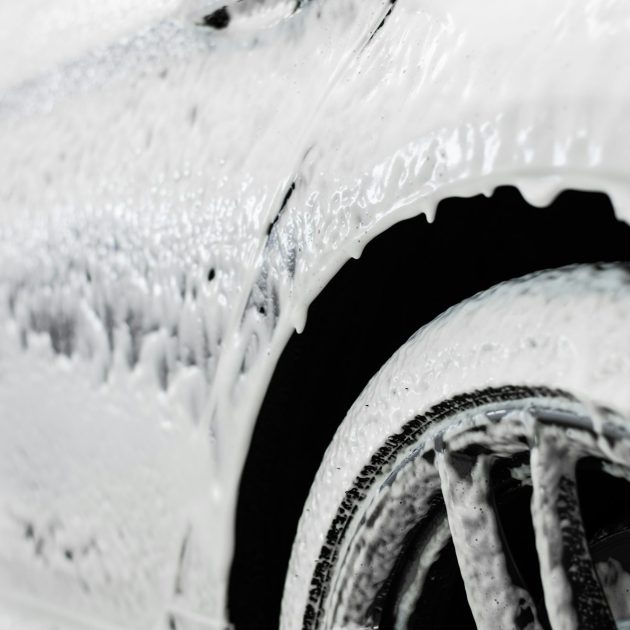 Car wash. The car thresholds is covered with white flowing foam at a carwash