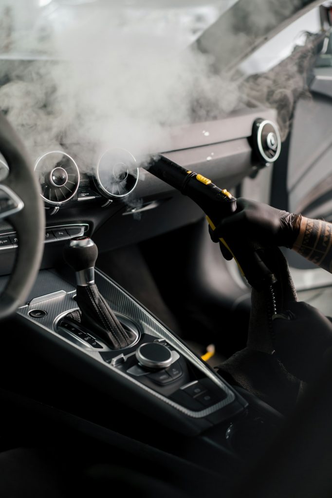 The detailing master cleans the car interior with hot steam cleaner Cleaning the car interior